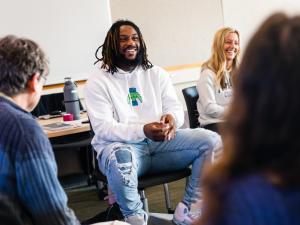 Graduate Student laughing in classroom, surrounded by other students