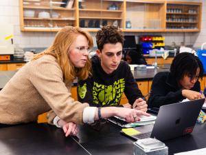 Faculty member helping student pointing to laptop