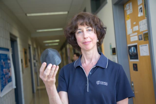 A woman holding a model asteroid