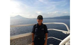 A woman in a US Navy uniform stands on the deck of a Naval vessel. 