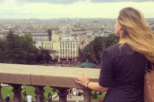 A long-haired woman gazing out over the city of Paris