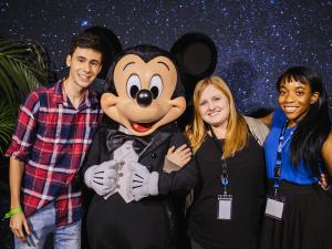 Three alumni pose with Mickey Mouse