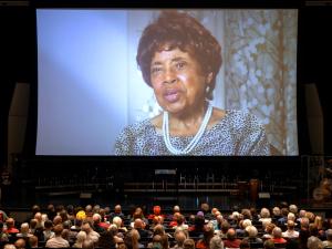 A photo of an older woman shone on an auditorium screen