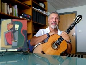 A man posing with a guitar and an abstract painting
