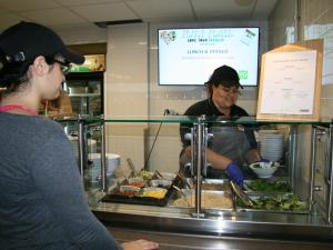 A woman at a counter puts food in a bowl