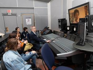 man in front of an audio mixing board teaches students