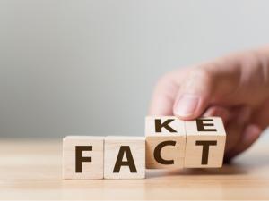 A hand moving lettered blocks spelling FAKE to FACT