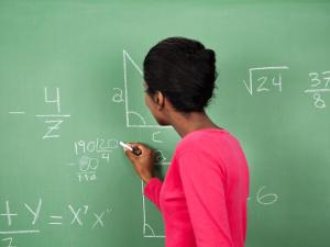 Woman at chalkboard writing a math equation 