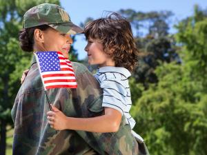 female soldier hugging boy holding US flag