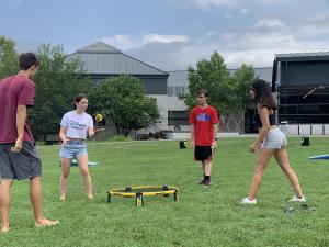 Four students playing spikeball on the campus center lawn