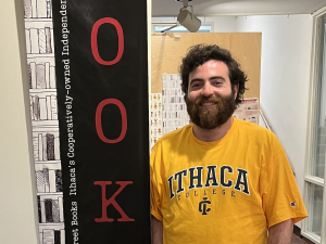Photo of a man standing by a books sign.