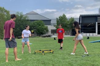 Four students playing spikeball on the Campus Center lawn.