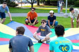 Students playing with a giant parachute at field day events during orientation