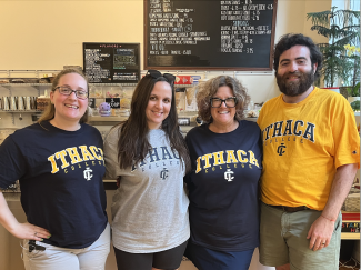 Four people wearing Ithaca College t-shirts standing in front of an ice cream shop.