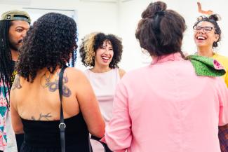 People in an art gallery laugh and converse. 