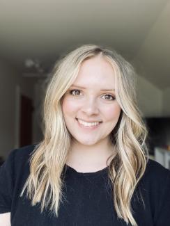 Picture of a woman with blonde hair wearing a black shirt smiling at the camera.