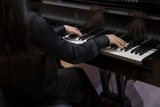 A picture of hands on a grand piano keyboard.