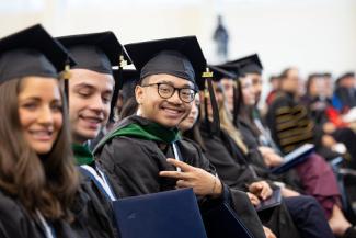 group of smiling students in caps and gowns