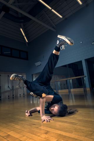 A breakdancer on the floor of a dance studio spinning their legs in the air
