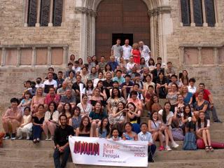 Students and Teachers gather on the steps of a building with a banner that reads "Music Fest Perugia 2022"