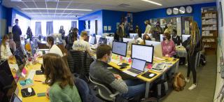 Students sit and stand at computer stations while working on production of The Ithacan.