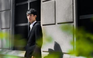 pianist Eric Lu stands outside in the sun, against a stone building