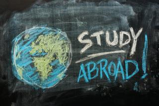 A blackboard with a globe drawn in blue and green chalk, with the words STUDY ABROAD! written next to it.