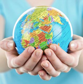 A small globe, cupped in someone's hands and held out to the viewer.