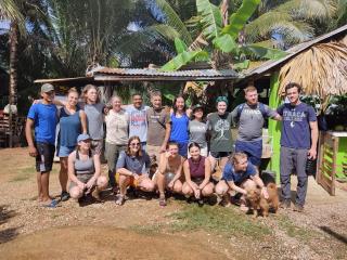 A group of Ithaca College students posing together in Belize, against a backdrop of palm trees and greenery.