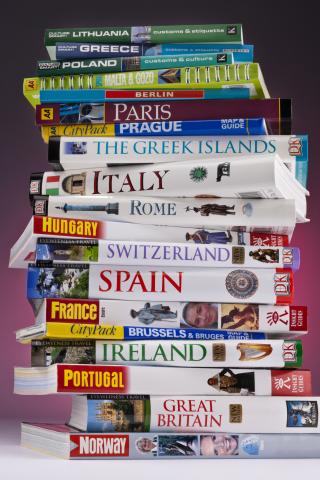 A tall pile of travel books focusing on European cities and countries