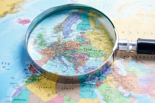A colorful world map, with a magnifying glass focused on Europe