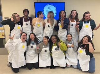 Spring 2024 SLC staff posing in their painting aprons.