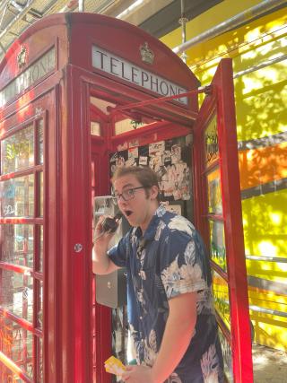 A college student standing inside an iconic British red phone booth