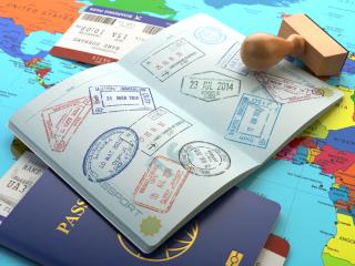 A passport with many different travel stamps on its pages, set on a world map