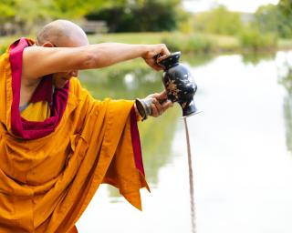 Tibetan monk pouring sand into a pond.