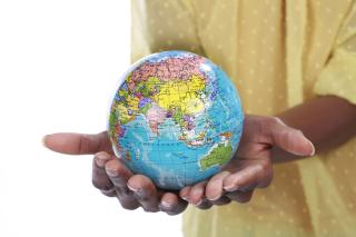 Two hands holding a small globe