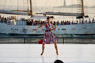 Vanessa Martínez de Baños dancing in front of the Hudson River with the Statue of Liberty behind her.