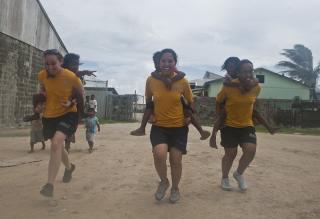 Three women give children piggy-back rides.